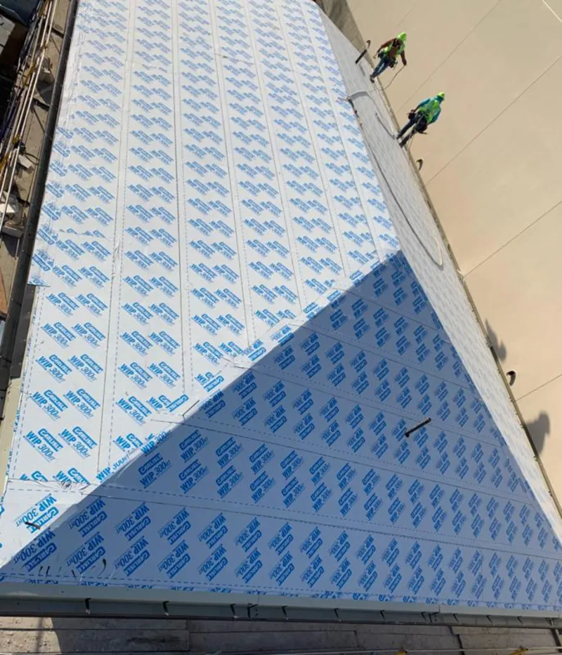 Professional roofers installing underlayment on a metal roof in Warren